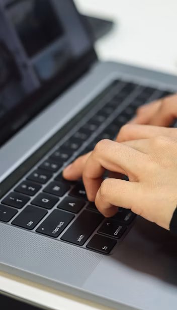 Hands type on a laptop keyboard.