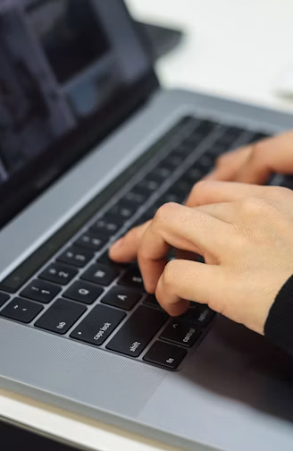 Hands type on a laptop keyboard.